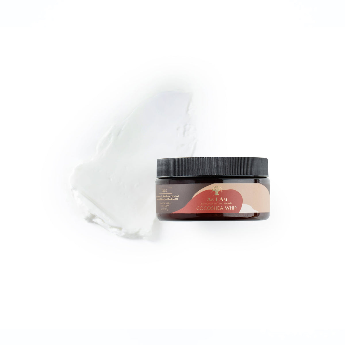 En brun plastik dåse med en etiket indeholder As I Am CocoShea Whip. Produktet er en leave-in conditioner til krøllet hår og har en cremet konsistens. Krukken står på en hvid baggrund, og der er en smule af produktet smurt ud ved siden af.