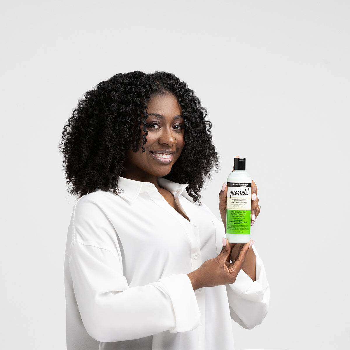 Kbinde der holder en lysegrøn flaske Aunt Jackie's Quench Moisture Intensive Leave-In Conditioner med sort låg.