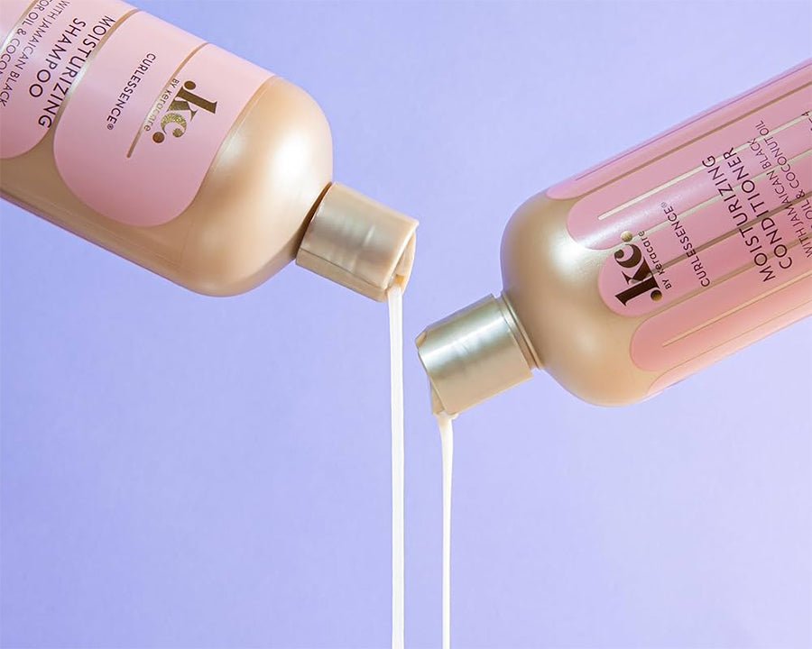 Keracare Curlessence Moisturizing Shampoo og Moisturizing Conditioner hældes ud mod en lilla baggrund.