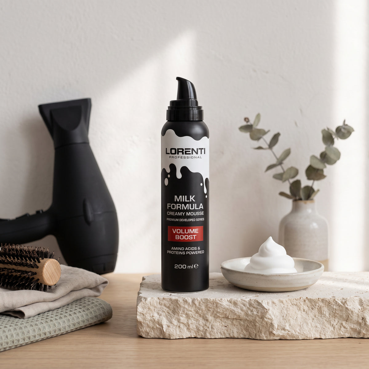 Lorenti Professional Milk Formula Creamy Mousse Volume Boost, 200 ml, sort pumpeflaske med skum, hårtørrer og børste i baggrunden.