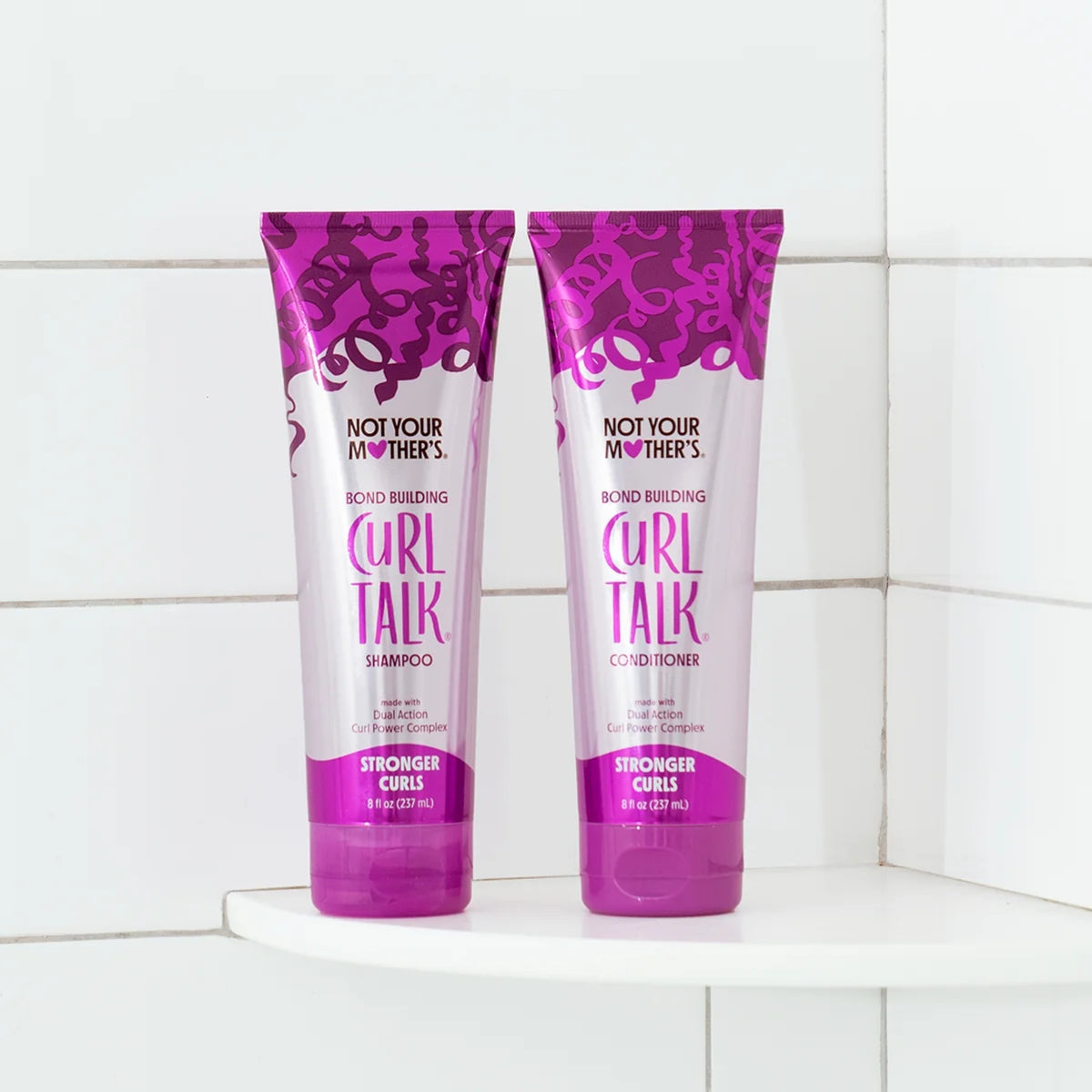 Not Your Mother's Curl Talk shampoo og conditioner i lilla tuber på hvid badeværelseshylde.