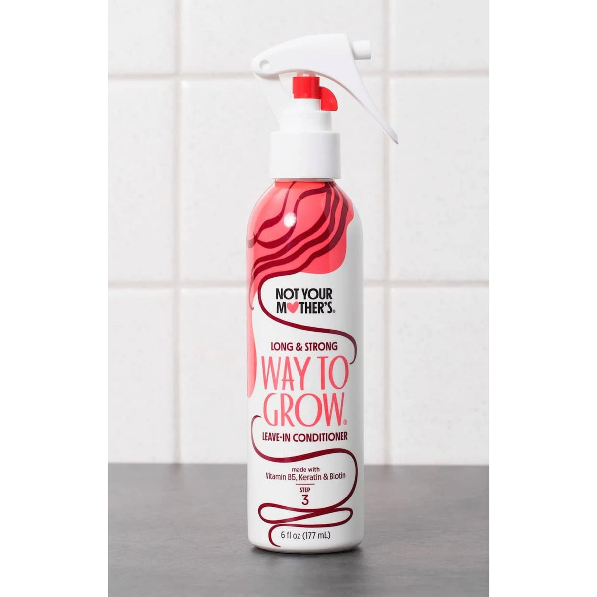 Not Your Mother's Way to Grow leave-in conditioner i sprayflaske med rødt mønster på køkkenbord.